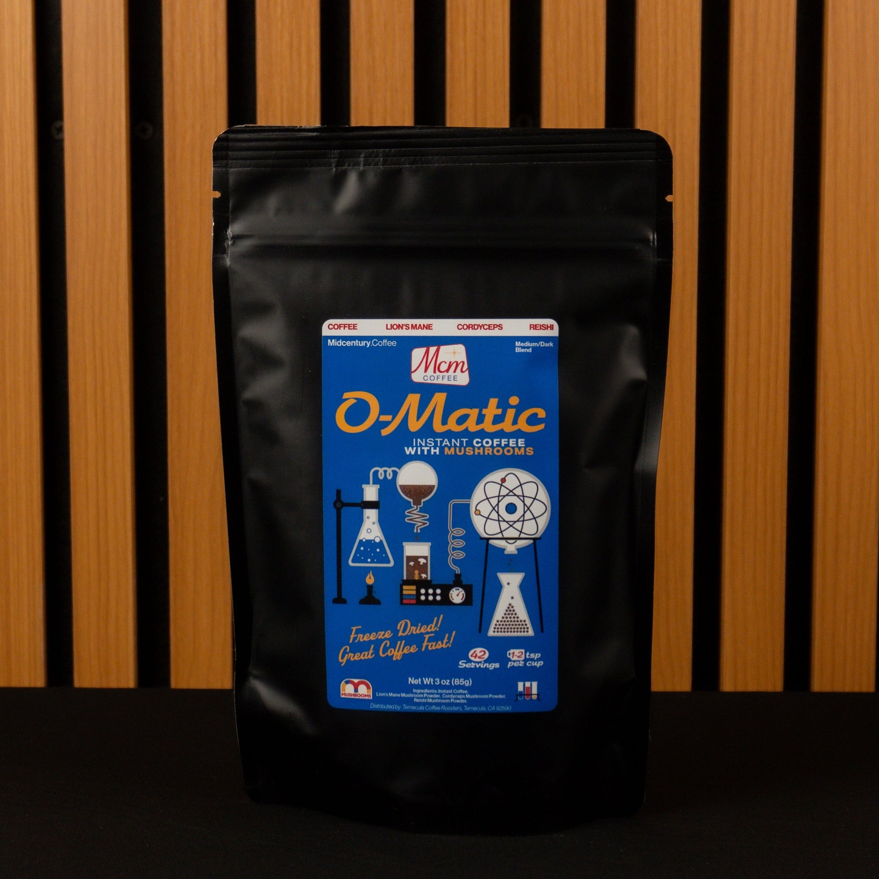 Black O-Matic Instant coffee with mushrooms package against a wooden slat background