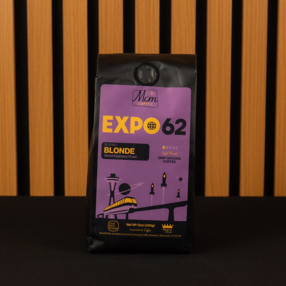 Purple coffee package labeled 'Expo 62 Blonde' against a wooden slatted background