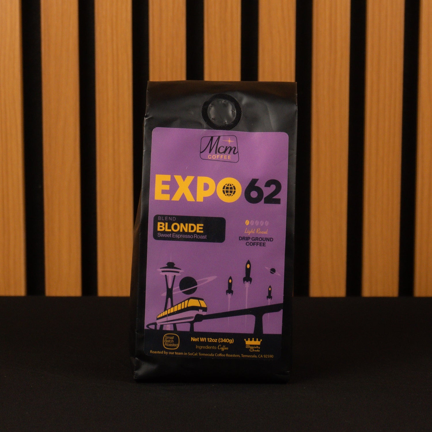 Purple coffee package labeled 'Expo 62 Blonde' against a wooden slatted background
