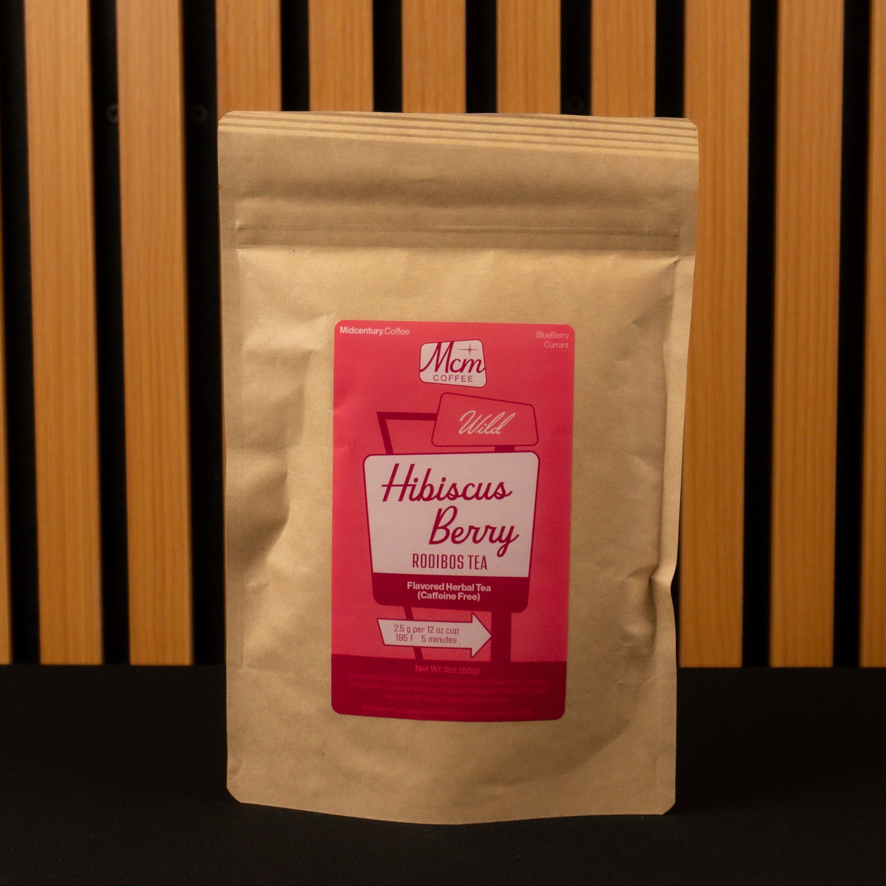 Kraft paper tea bag with a red label featuring 'Mam' branding on a wooden background.
