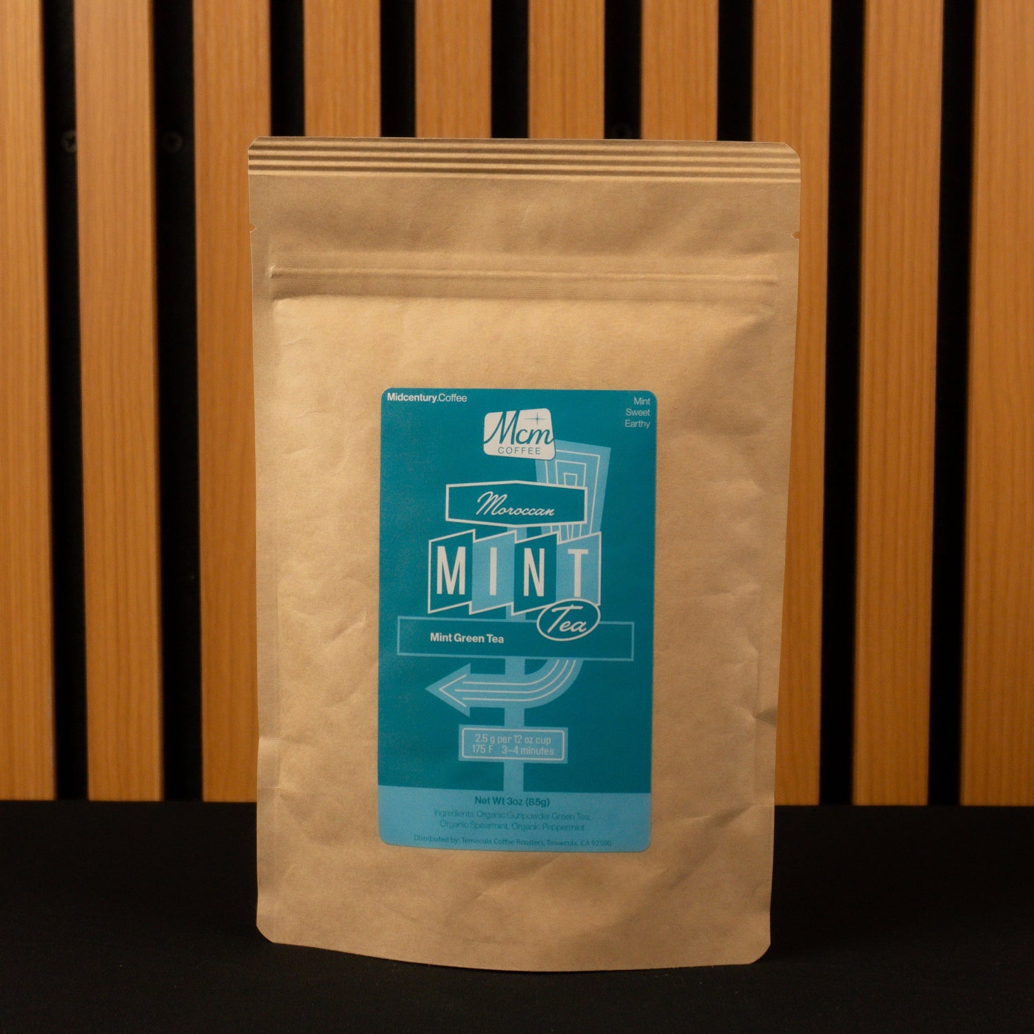 Kraft paper coffee bag with a teal label on a wooden slatted background