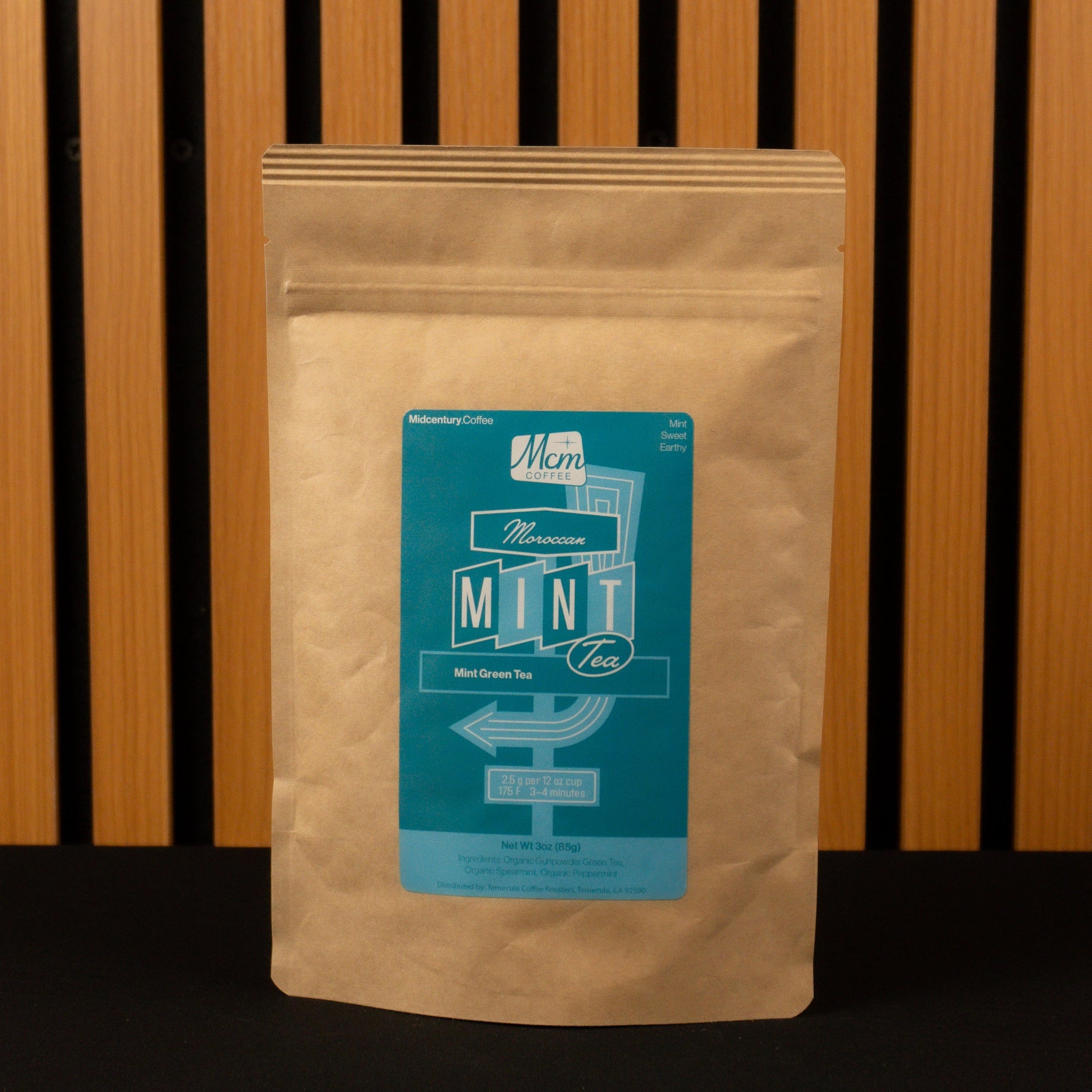 Kraft paper coffee bag with a teal label on a wooden slatted background