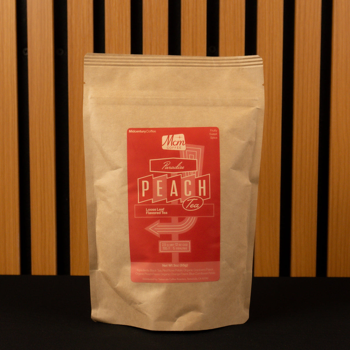 Kraft paper coffee bag with a red label featuring 'Peach' on a wooden slatted background.