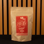 Kraft paper coffee bag with a red label featuring 'Peach' on a wooden slatted background.