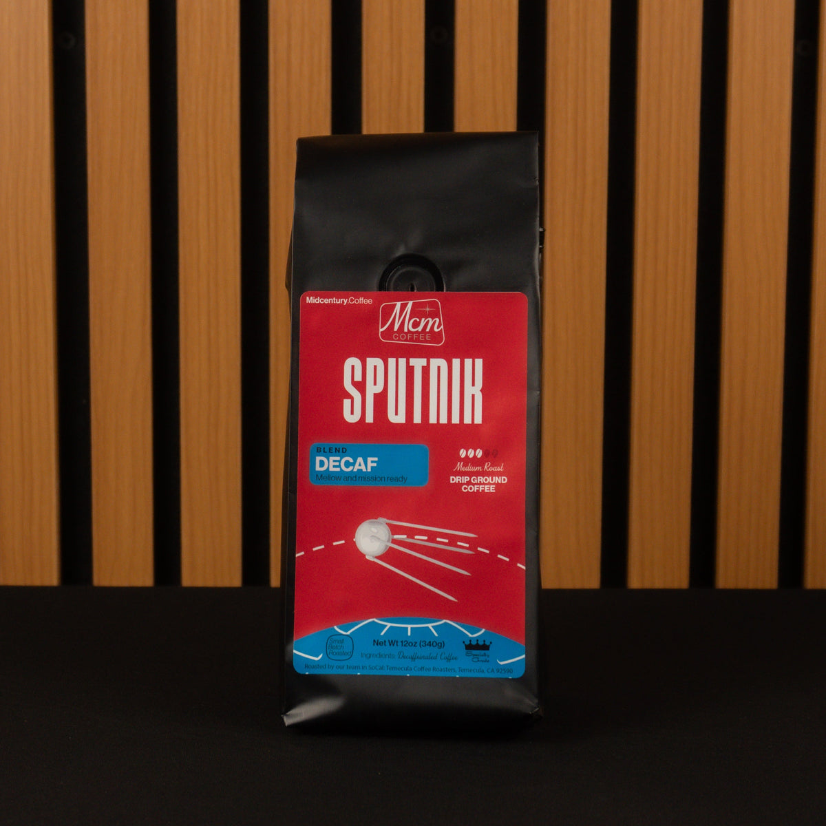 Coffee package labeled 'Sputnik Decaf' on a wooden slat background